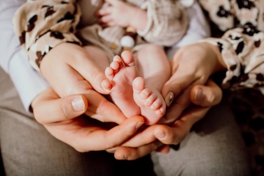 noworodkowe stopy, rodzice trzymają w rękach stopy noworodka podczas sesji zdjęciowej w domu, fotografia noworodkowa Katowice