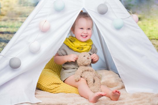 zdjęcie dziecka siedzącego w namiocie tipi