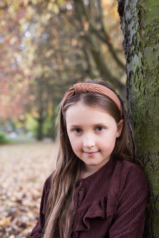 zdjęcie dziewczynki na tle jesiennych drzew,  jesienna sesja dziecka w plenerze,